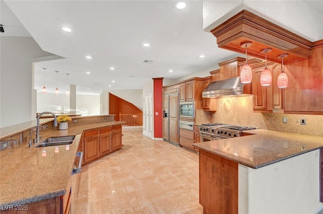 kitchen with wall chimney exhaust hood, appliances with stainless steel finishes, decorative light fixtures, a peninsula, and a sink