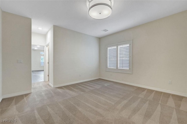 unfurnished room featuring baseboards, visible vents, and light colored carpet