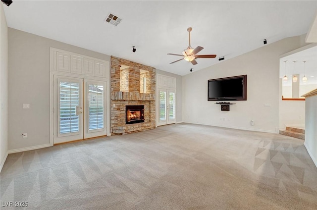 unfurnished living room with a glass covered fireplace, visible vents, lofted ceiling, and carpet flooring