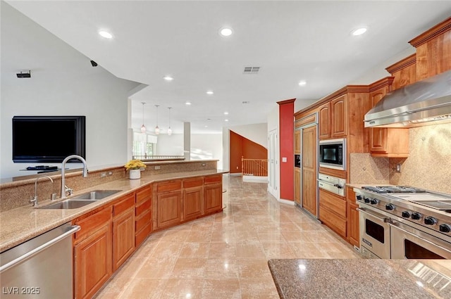 kitchen with stainless steel appliances, a sink, visible vents, backsplash, and wall chimney exhaust hood