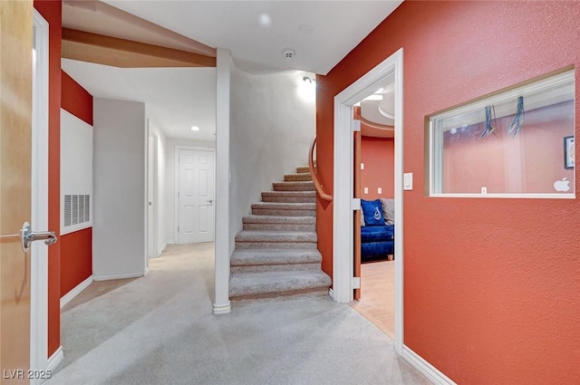 hallway featuring light carpet, stairs, and baseboards