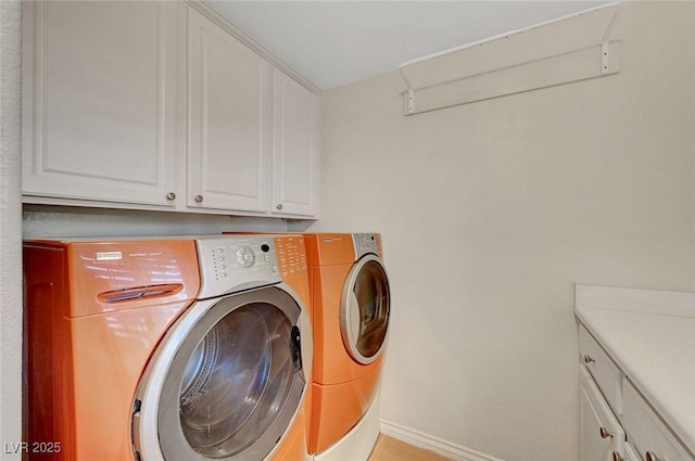 clothes washing area with cabinet space, baseboards, and washing machine and clothes dryer