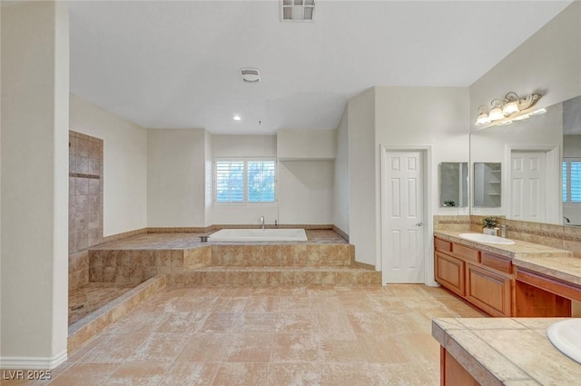 bathroom featuring visible vents, a garden tub, and vanity