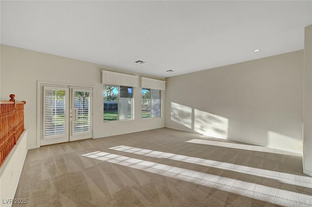 unfurnished room featuring french doors, visible vents, and light colored carpet