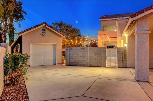 exterior space featuring an outbuilding, concrete driveway, a gate, and stucco siding