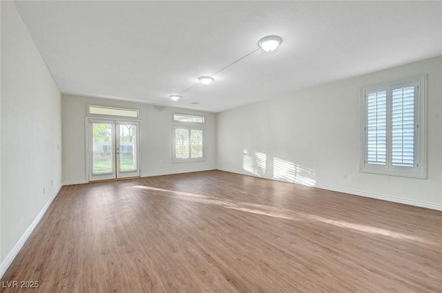 empty room featuring baseboards, wood finished floors, and french doors