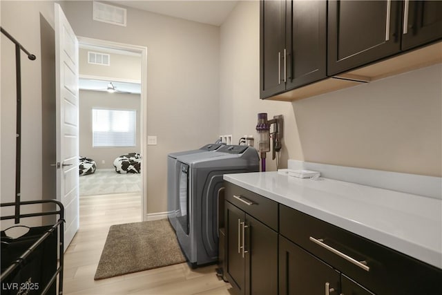 laundry area featuring light hardwood / wood-style floors, washing machine and dryer, and cabinets