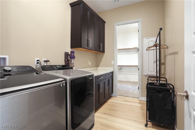 washroom featuring cabinets, washing machine and dryer, and light hardwood / wood-style flooring