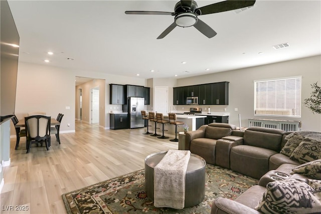 living room with ceiling fan and light wood-type flooring