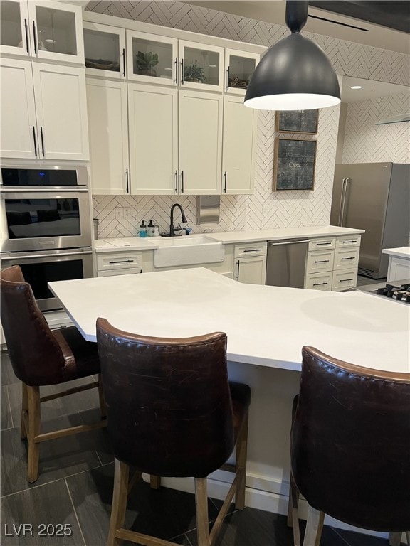 kitchen with stainless steel appliances, sink, white cabinets, and backsplash