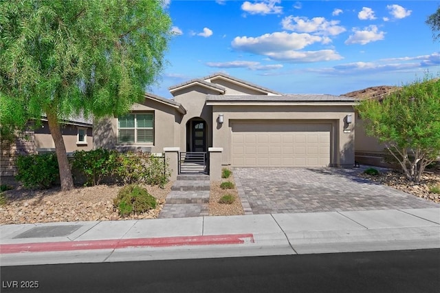 ranch-style home featuring a garage, a tiled roof, decorative driveway, and stucco siding