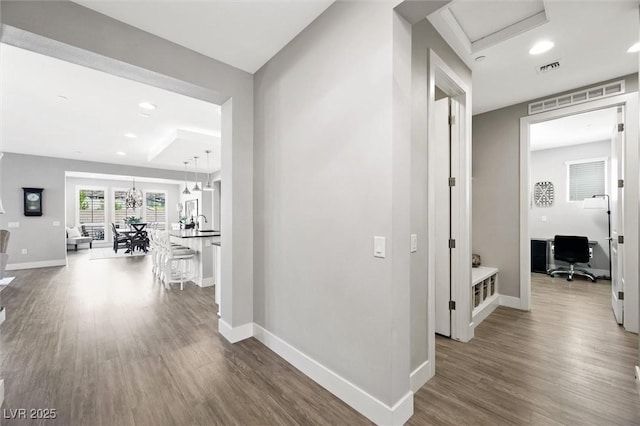 corridor featuring wood finished floors, visible vents, and baseboards