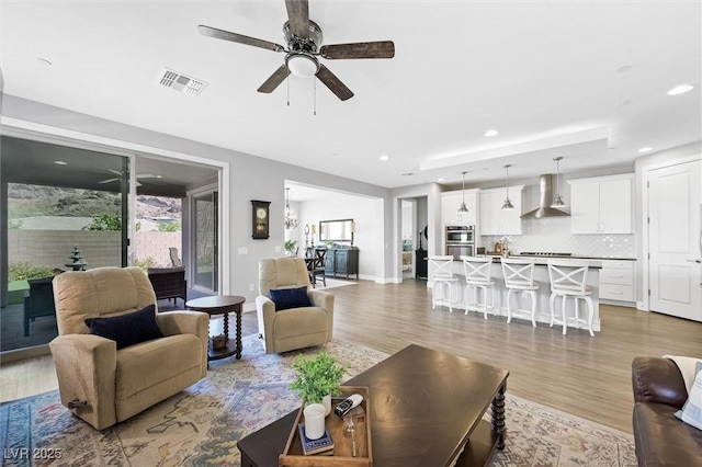 living room featuring ceiling fan, light wood finished floors, visible vents, and recessed lighting