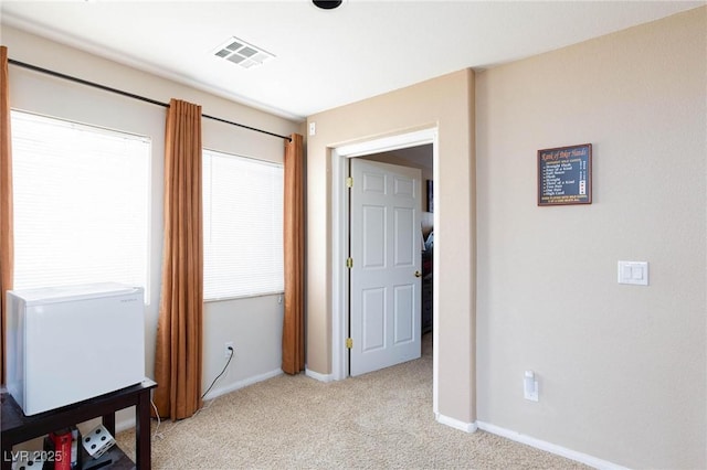 hall with light colored carpet and a healthy amount of sunlight