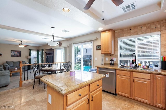 kitchen with a kitchen island, pendant lighting, sink, stainless steel dishwasher, and a tray ceiling