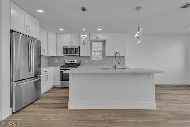 kitchen with stainless steel appliances, decorative light fixtures, sink, and white cabinets