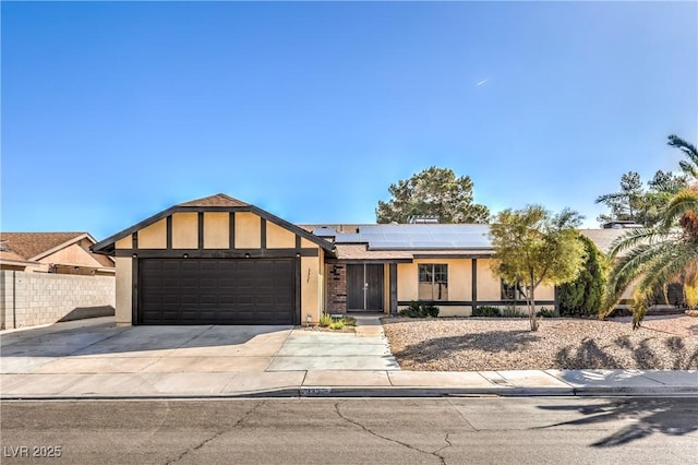 view of front of property featuring fence, driveway, solar panels, stucco siding, and a garage