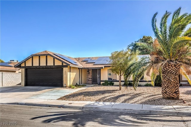 view of front facade featuring concrete driveway, a garage, roof mounted solar panels, and stucco siding