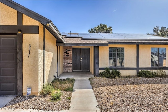 view of exterior entry with stucco siding and solar panels