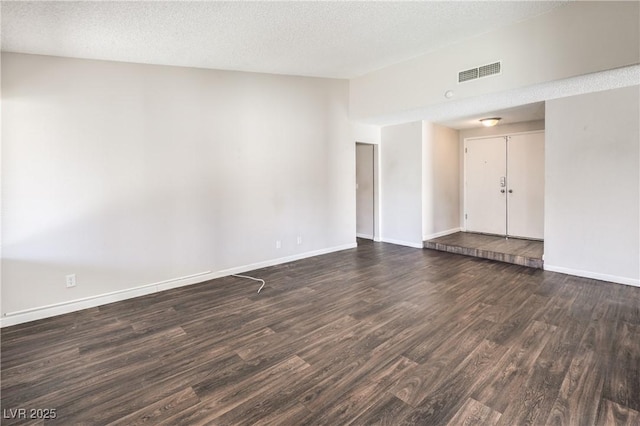 empty room featuring visible vents, baseboards, lofted ceiling, a textured ceiling, and dark wood-style flooring