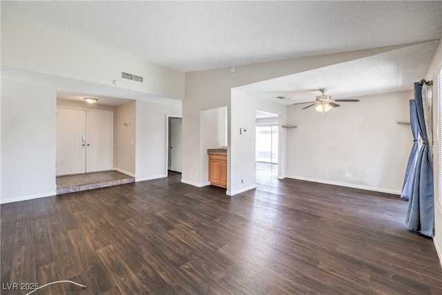 unfurnished living room featuring dark wood-type flooring, baseboards, visible vents, and a textured ceiling