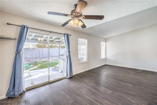 empty room featuring ceiling fan, baseboards, a textured ceiling, and dark wood-style floors