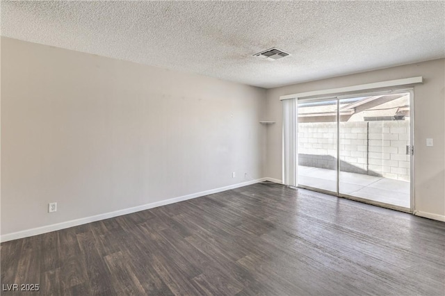 spare room featuring dark wood-style floors, visible vents, a textured ceiling, and baseboards