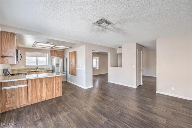 kitchen with visible vents, a sink, stainless steel appliances, a peninsula, and dark wood-style flooring