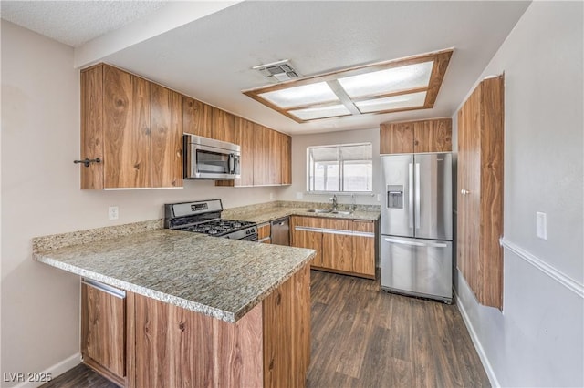 kitchen with stainless steel appliances, brown cabinets, and a peninsula