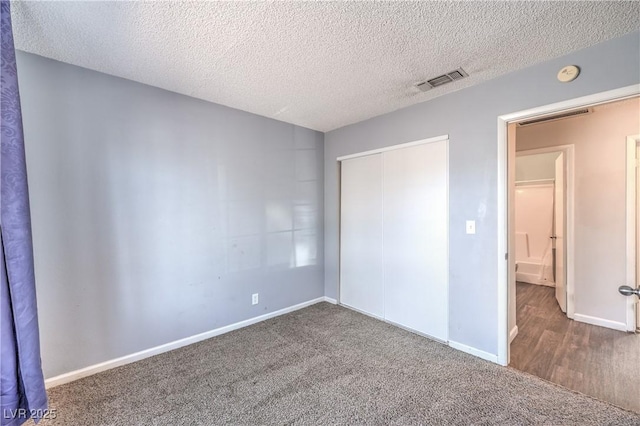 unfurnished bedroom featuring carpet, baseboards, visible vents, a closet, and a textured ceiling