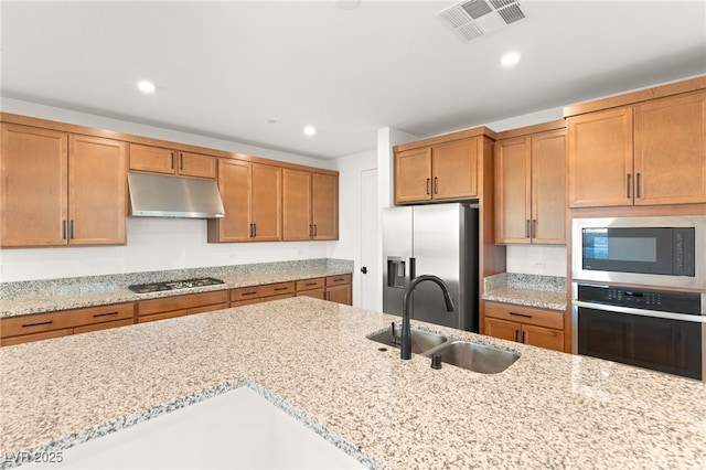 kitchen with appliances with stainless steel finishes, light stone countertops, and sink