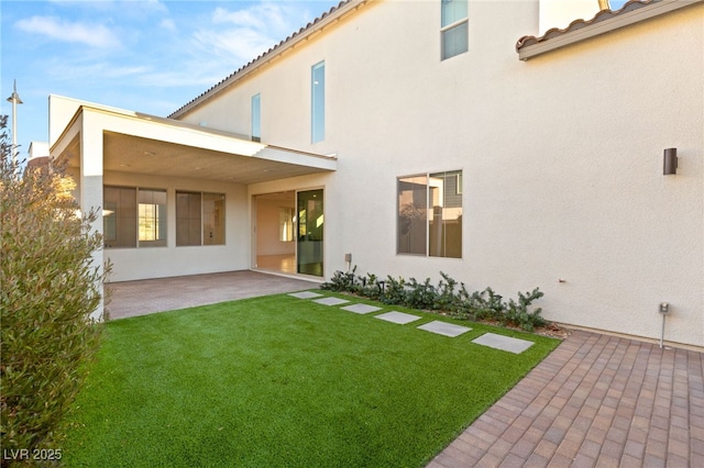 rear view of house with a lawn and a patio area