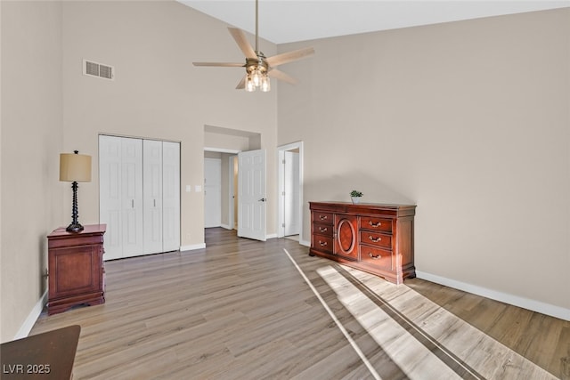 unfurnished bedroom with a closet, high vaulted ceiling, ceiling fan, and light hardwood / wood-style flooring