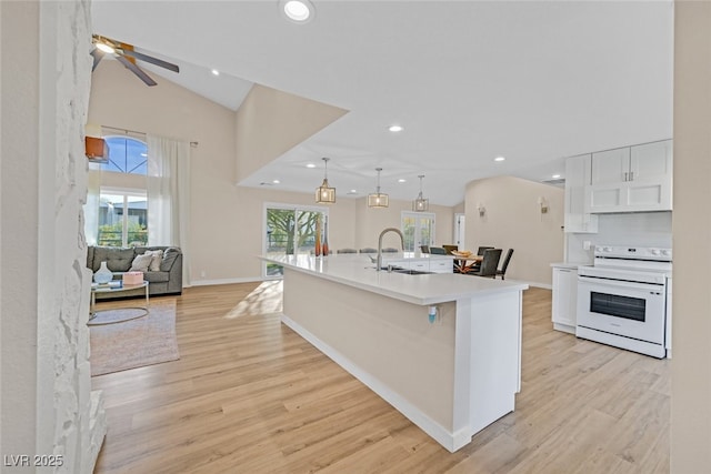 kitchen featuring electric stove, sink, hanging light fixtures, light hardwood / wood-style floors, and a spacious island