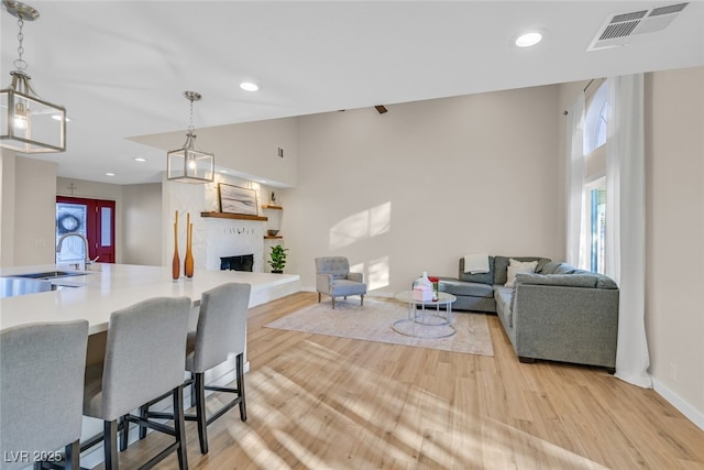 living room with high vaulted ceiling, sink, a wealth of natural light, and light hardwood / wood-style floors