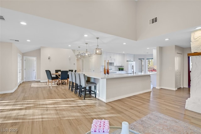 kitchen featuring a spacious island, white cabinetry, light hardwood / wood-style flooring, and pendant lighting