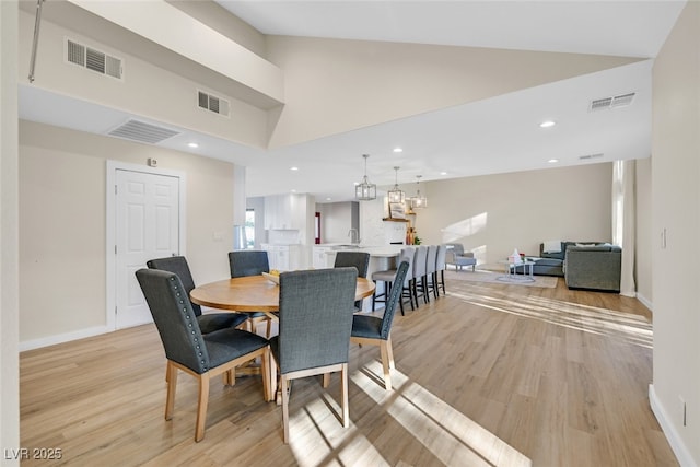 dining area featuring high vaulted ceiling and light hardwood / wood-style floors