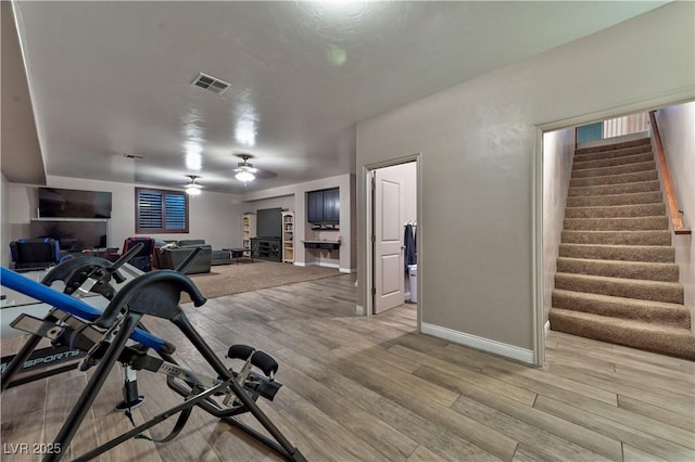 workout room with ceiling fan and light hardwood / wood-style flooring