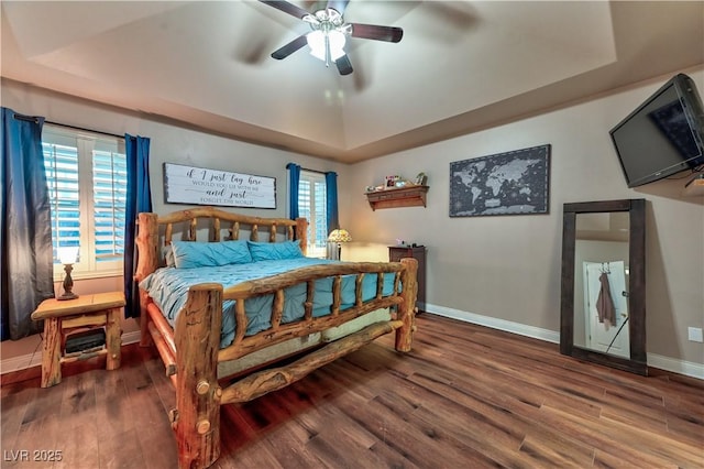 bedroom with ceiling fan, a raised ceiling, and hardwood / wood-style floors