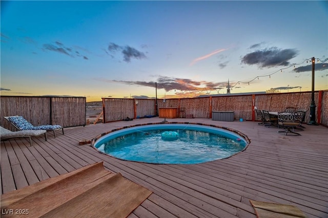 pool at dusk featuring a wooden deck