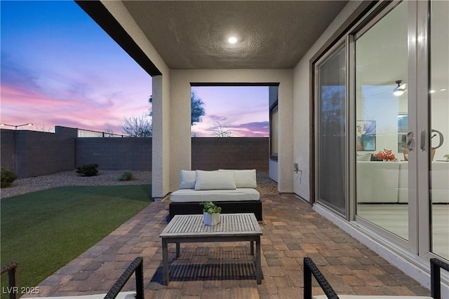 patio terrace at dusk with an outdoor living space and a lawn