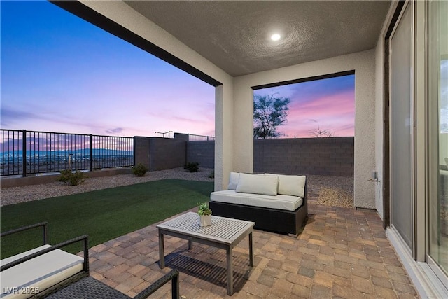 patio terrace at dusk featuring an outdoor hangout area and a lawn