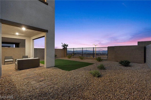 yard at dusk with an outdoor living space and a patio