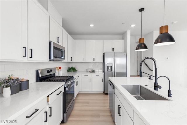 kitchen with stainless steel appliances, hanging light fixtures, sink, and white cabinets