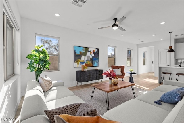 living room featuring ceiling fan, a wealth of natural light, and light wood-type flooring