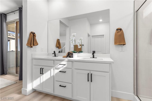 bathroom with an enclosed shower, wood-type flooring, and vanity