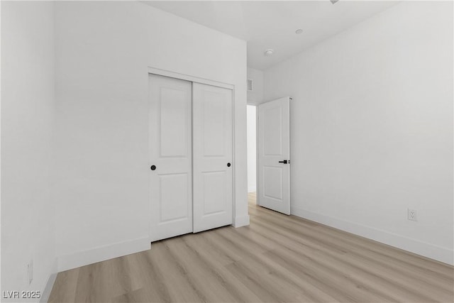 unfurnished bedroom with light hardwood / wood-style flooring and a closet