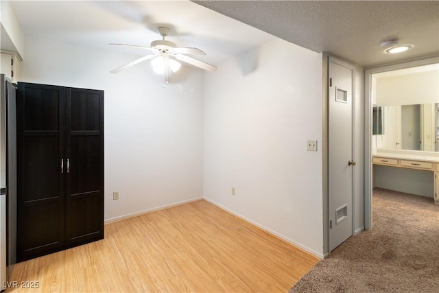 unfurnished bedroom with ceiling fan, a textured ceiling, and light wood-type flooring