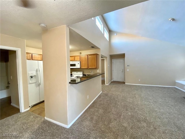 kitchen featuring a high ceiling, light colored carpet, white appliances, kitchen peninsula, and a textured ceiling