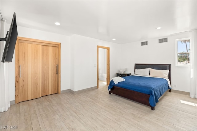 bedroom with ensuite bathroom and light hardwood / wood-style floors